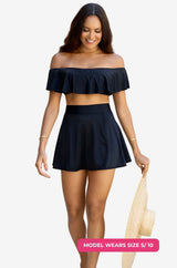 Black off-shoulder swim top and high-waisted swim skirt worn by a model size S/10 set on a grey background