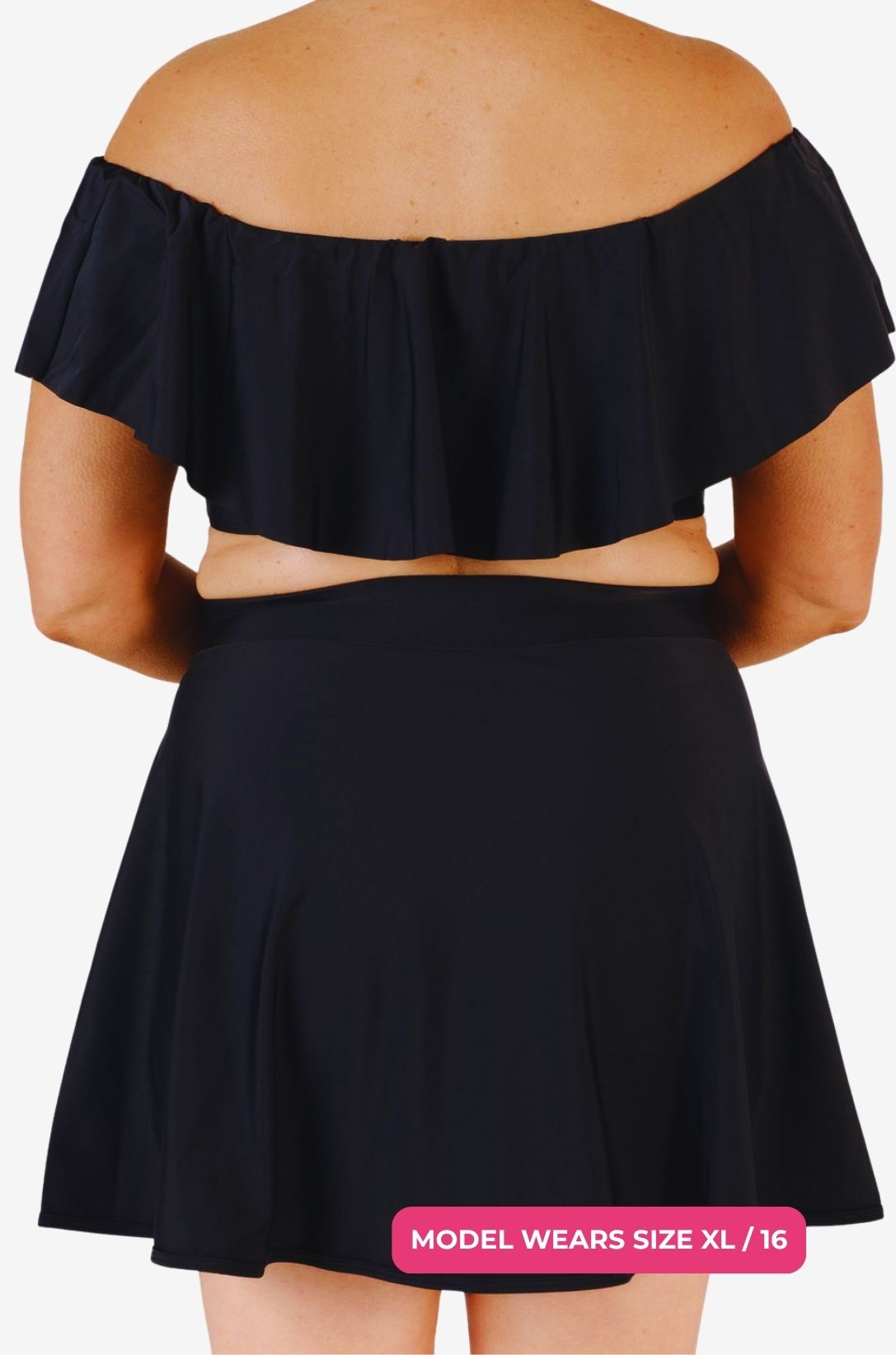 Back view of a black off-shoulder swim top and high-waisted swim skirt worn by a model size XL/16 set on a grey background