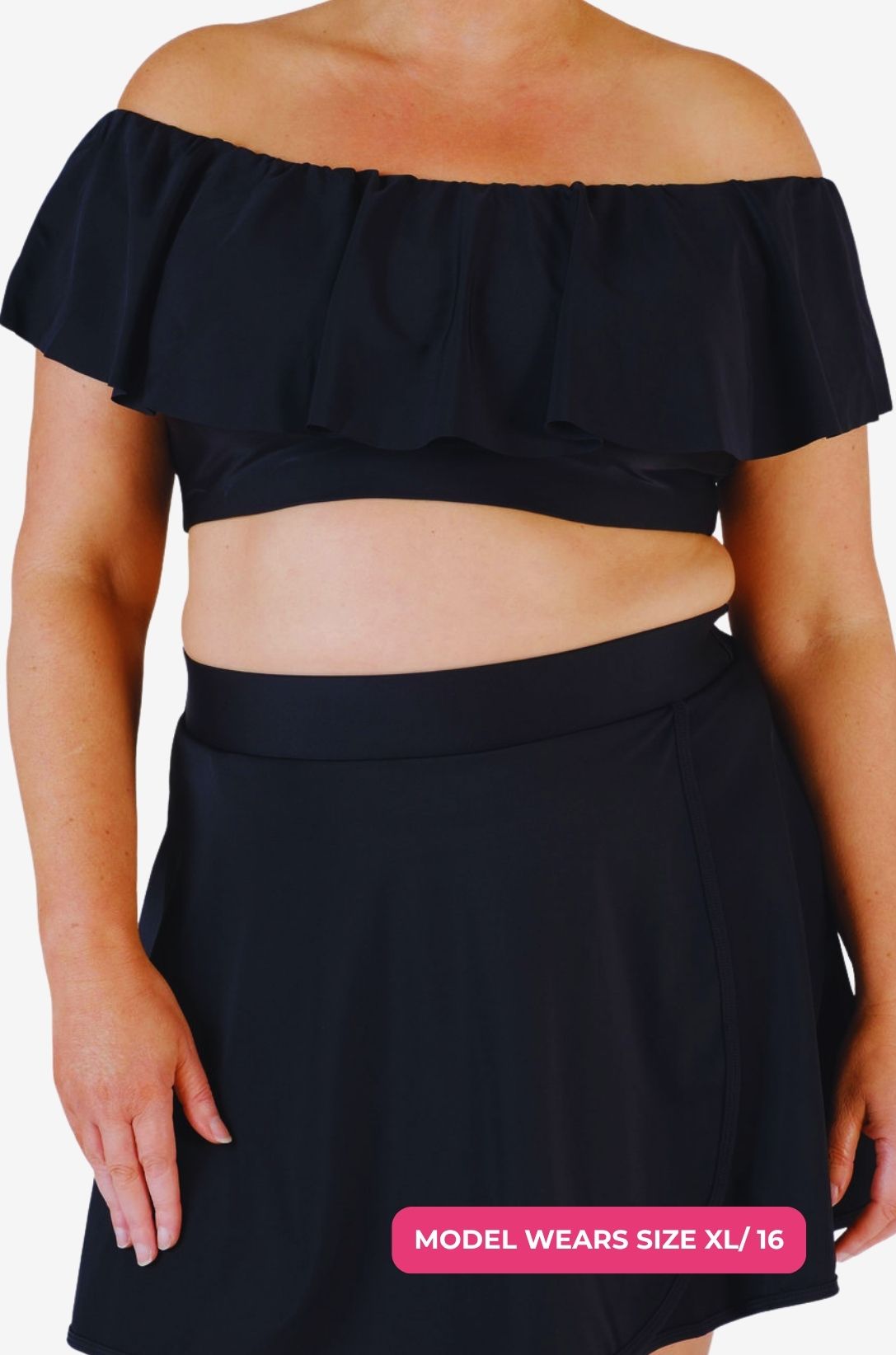 Black off-shoulder swim top and high-waisted swim skirt worn by a model size XL/16 set on a grey background