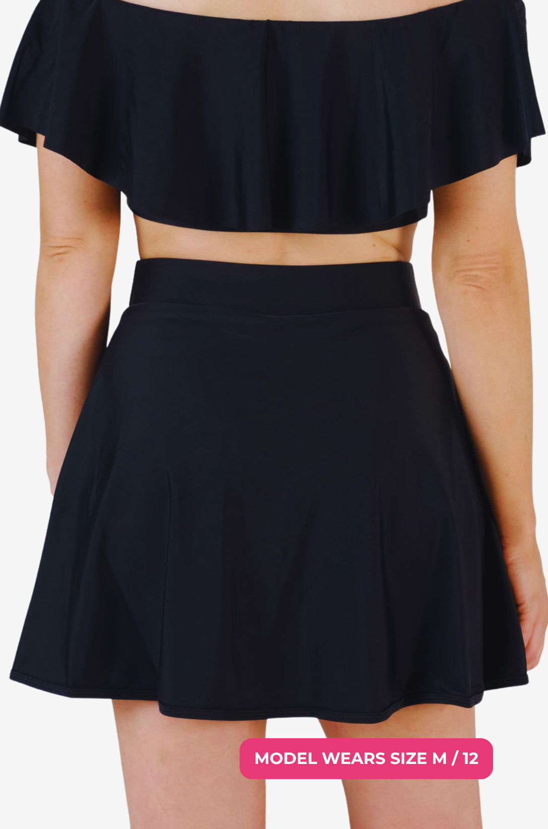 Back view of a black high-waisted swim skirt and matching top on a model size M/12 set on a grey background