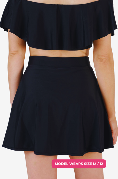 Back view of a black high-waisted swim skirt and matching top on a model size M/12 set on a grey background