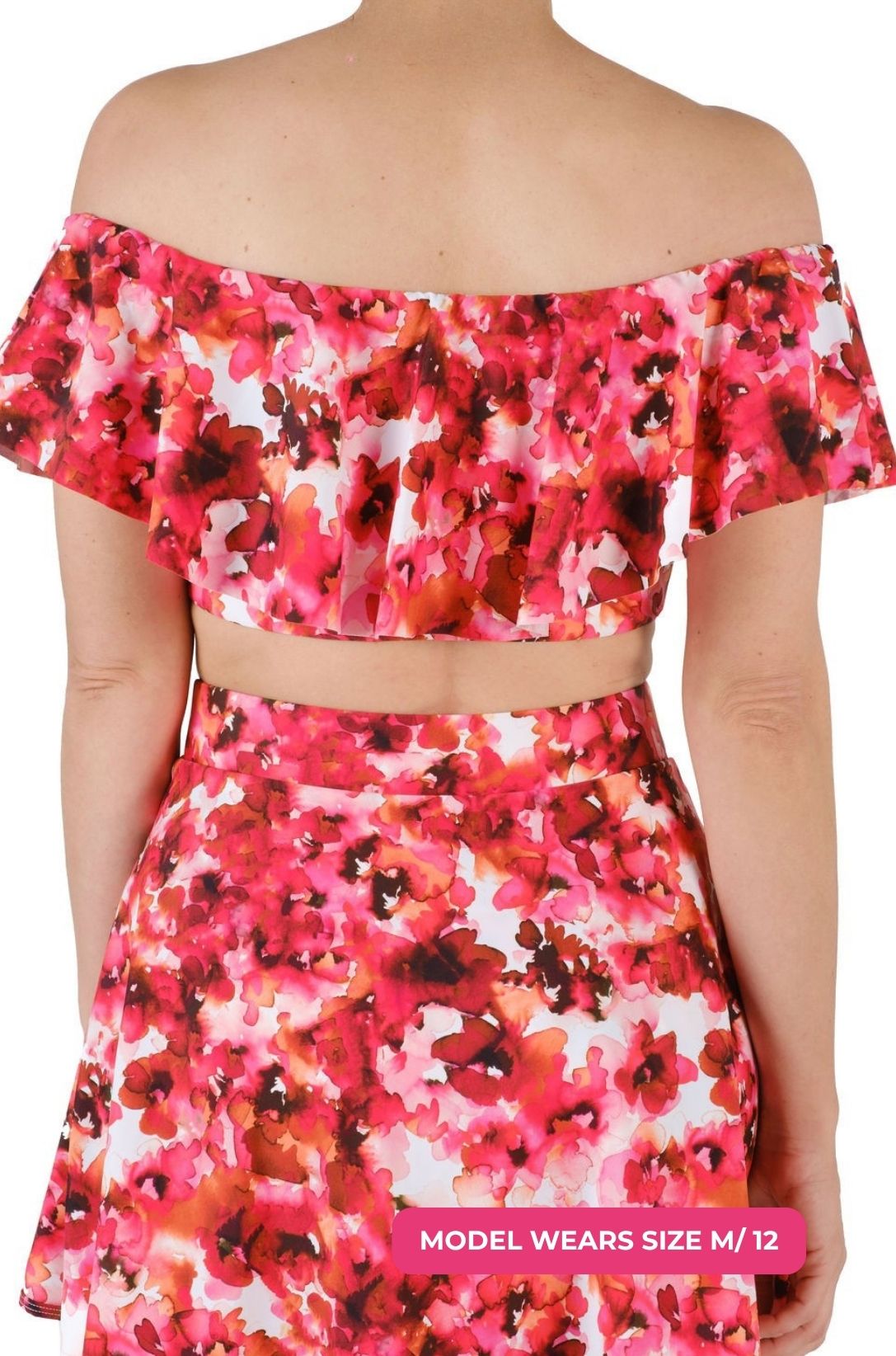 Back view of a model size M/12 wearing a floral off-shoulder swim top and high-waisted swim skirt set on a grey background