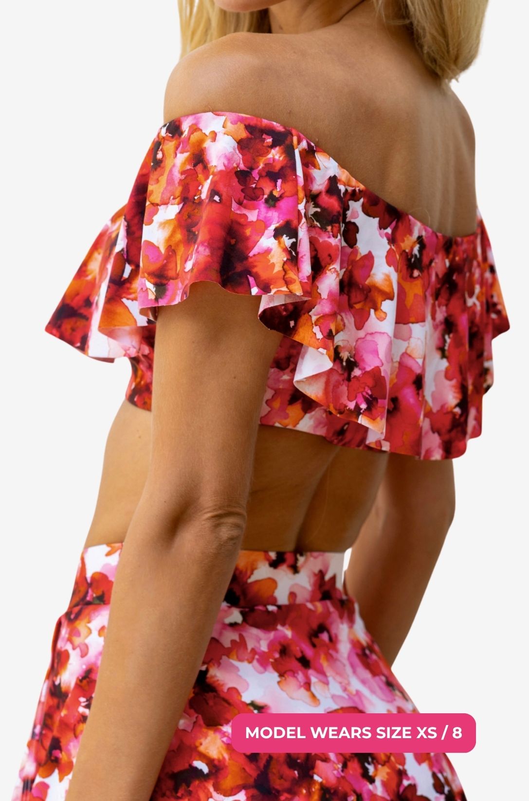 Side view of a model size XS/8 wearing a floral off-shoulder swim top and high-waisted swim skirt set on a grey background