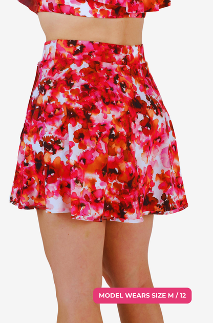 Side view of a model size M/12 wearing a floral high-waisted swim skirt on a grey background