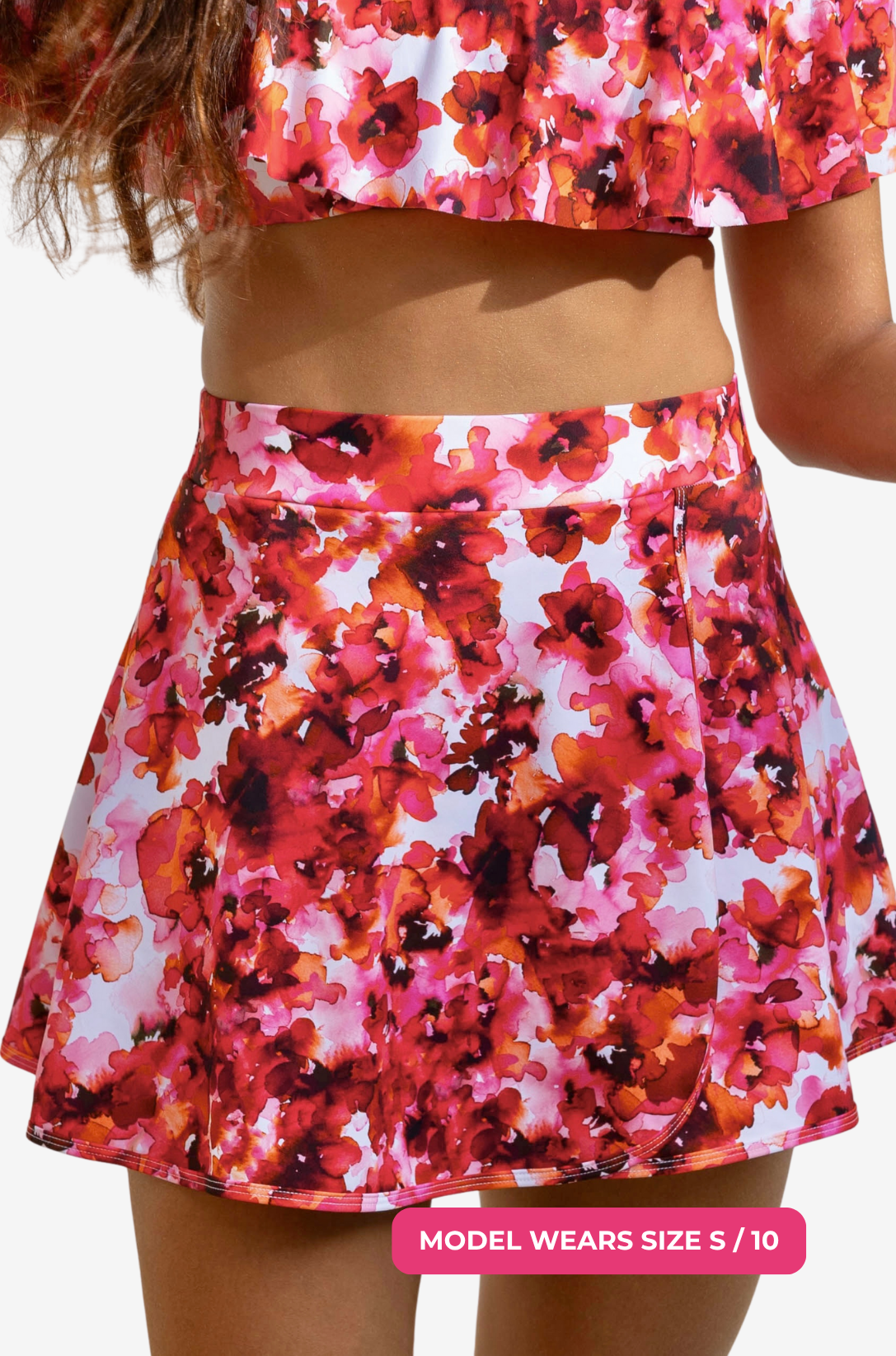 Model size S/10 wearing a red and pink floral high-waisted swim skirt set on a grey background