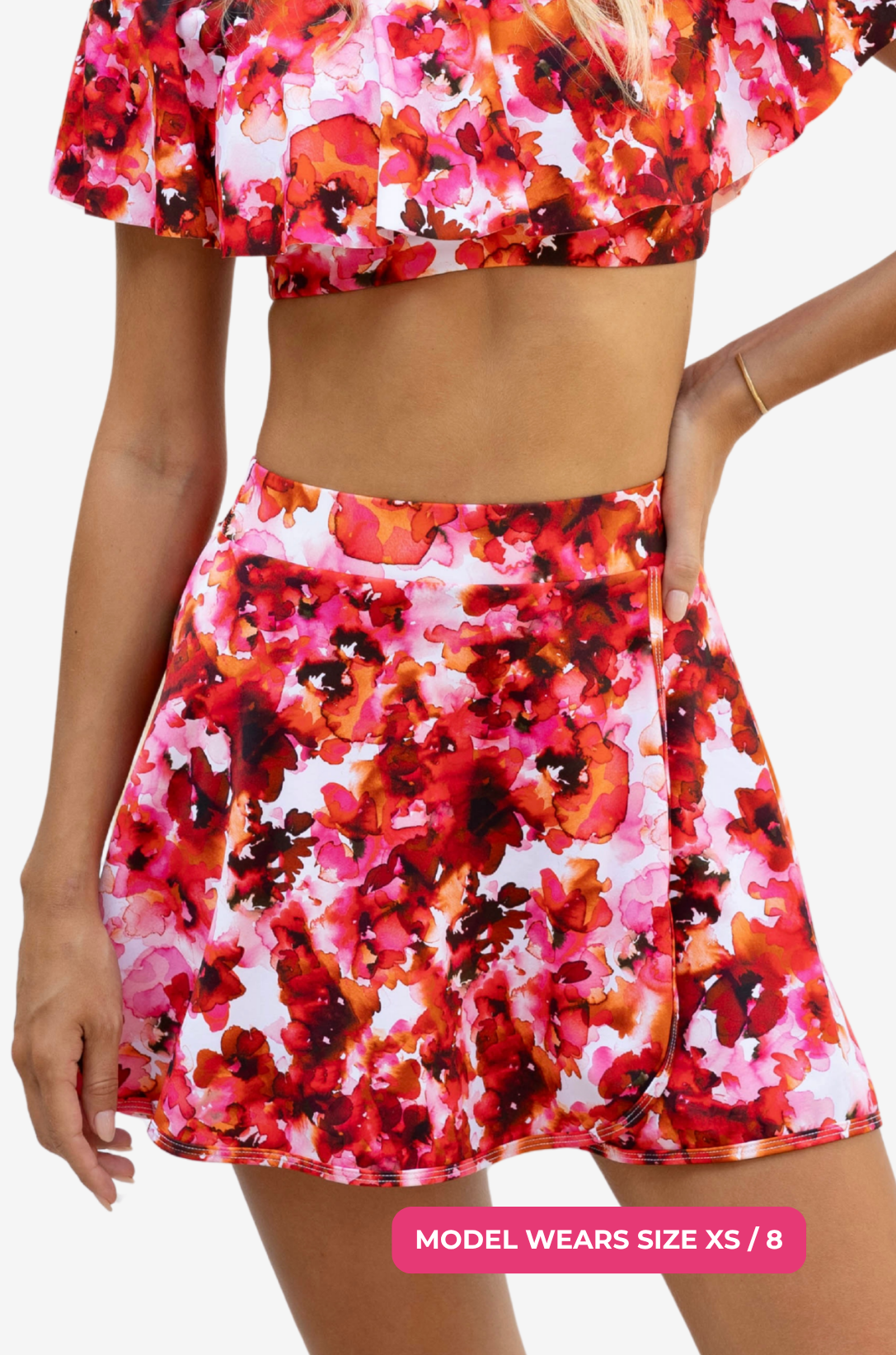 Model size XS/8 wearing a red and pink floral high-waisted swim skirt on a grey background