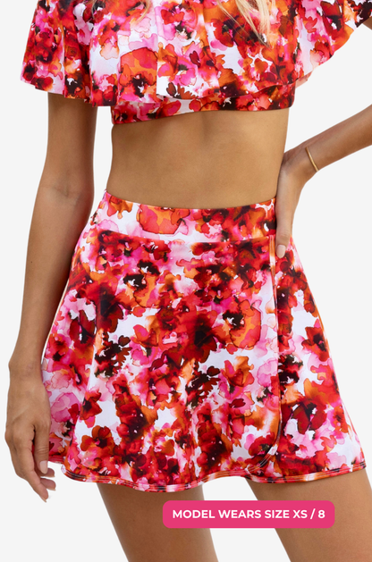 Model size XS/8 wearing a red and pink floral high-waisted swim skirt on a grey background