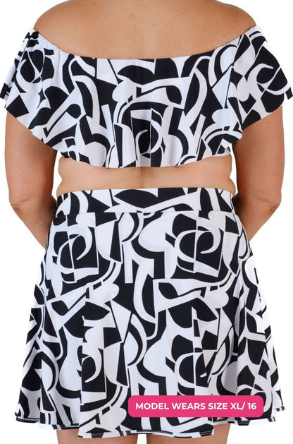 Back view of a black and white geometric patterned off-shoulder swim top worn on a model size XL/16