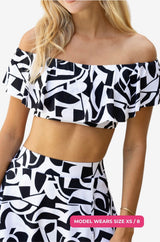 Close up of a black and white geometric patterned off-shoulder swim top worn on a model size XS/8