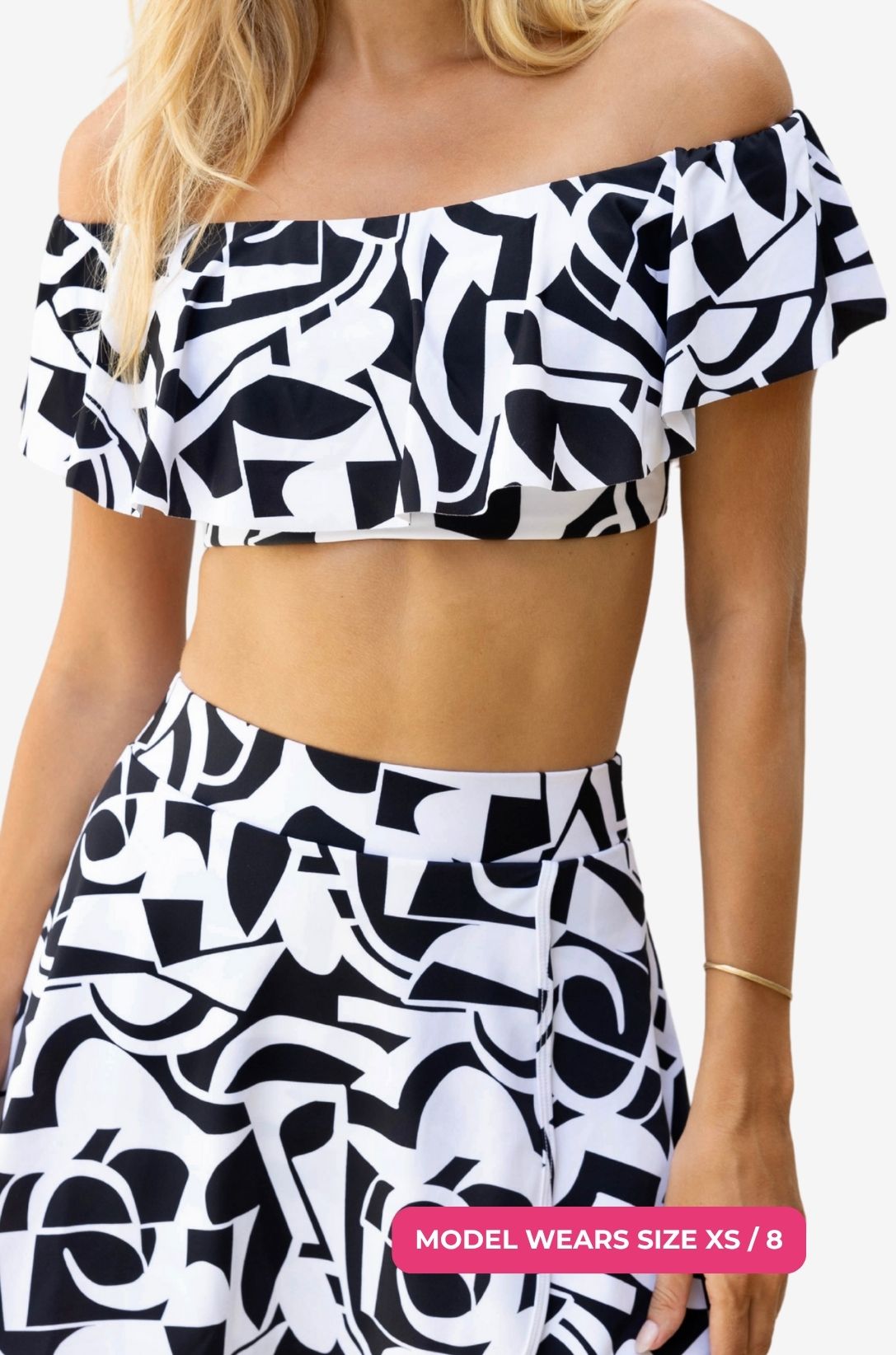 Close up of a black and white geometric patterned off-shoulder swim top worn on a model size XS/8