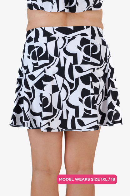 Back view of a model size 1XL/18 wearing a black and white geometric high-waisted swim skirt on a grey background